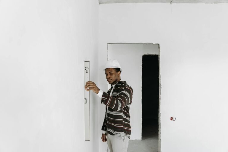 Architect wearing hard hat checks wall alignment in a renovation project.