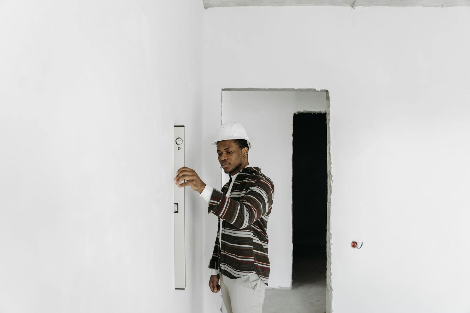 Architect wearing hard hat checks wall alignment in a renovation project.