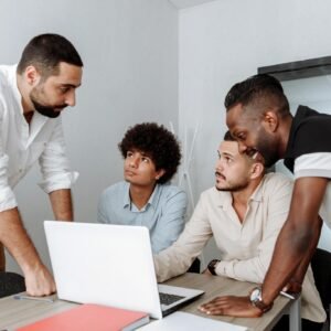 Diverse group of business professionals engaging in a collaborative meeting around a laptop.